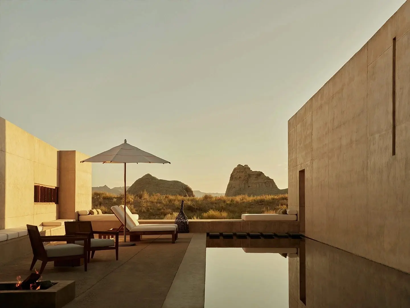A shaded pool terrace between concrete walls, desert rock formations beyond