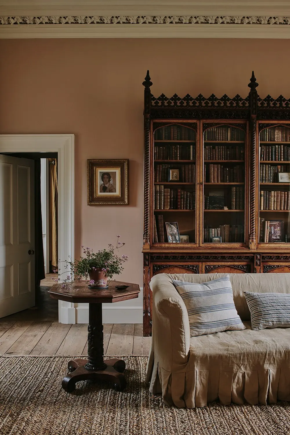 A quiet sitting room with a carved bookcase, a sofa and a round table