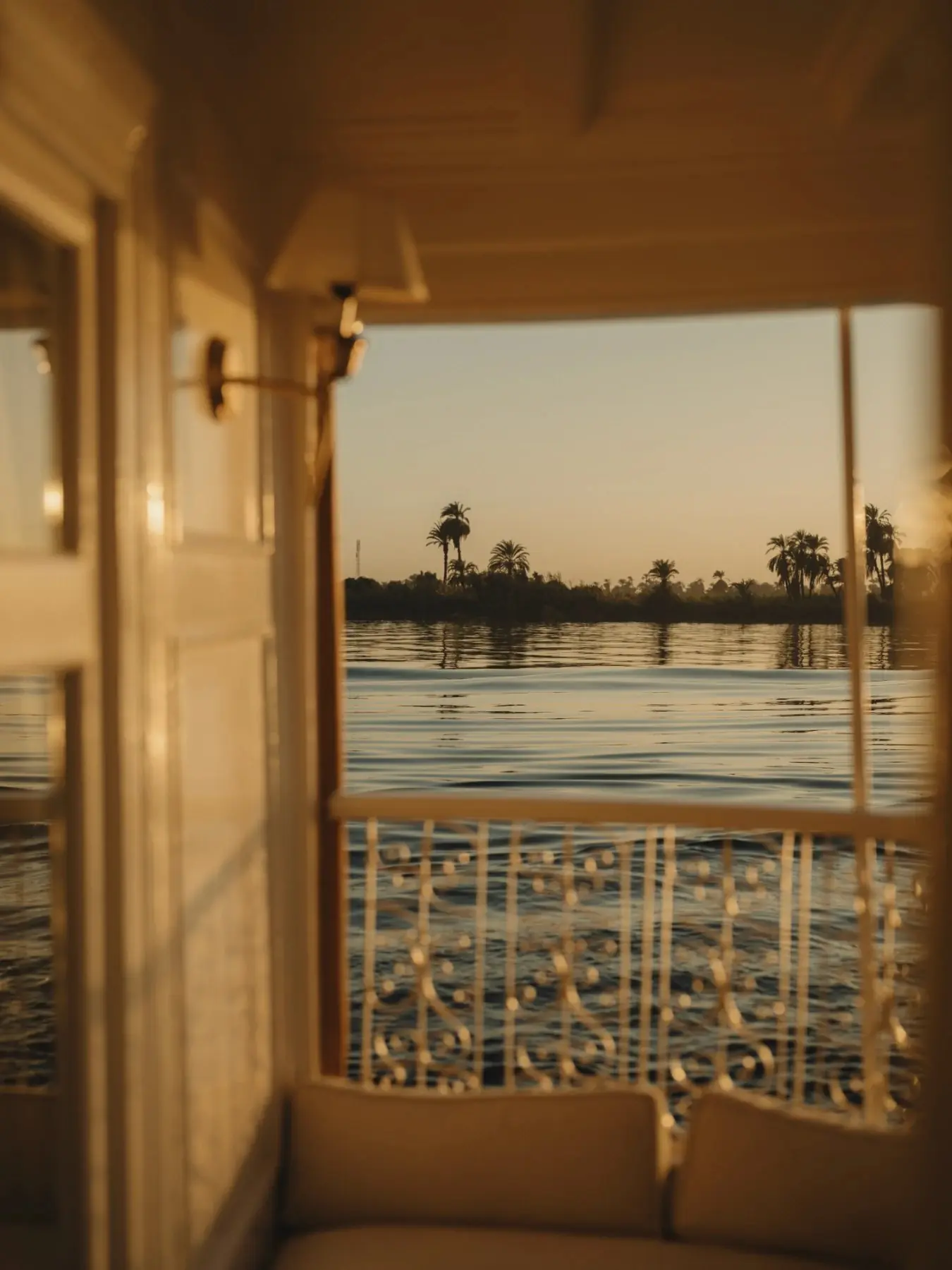 Sunset over a wide river, seen through the open window of a ship's cabin