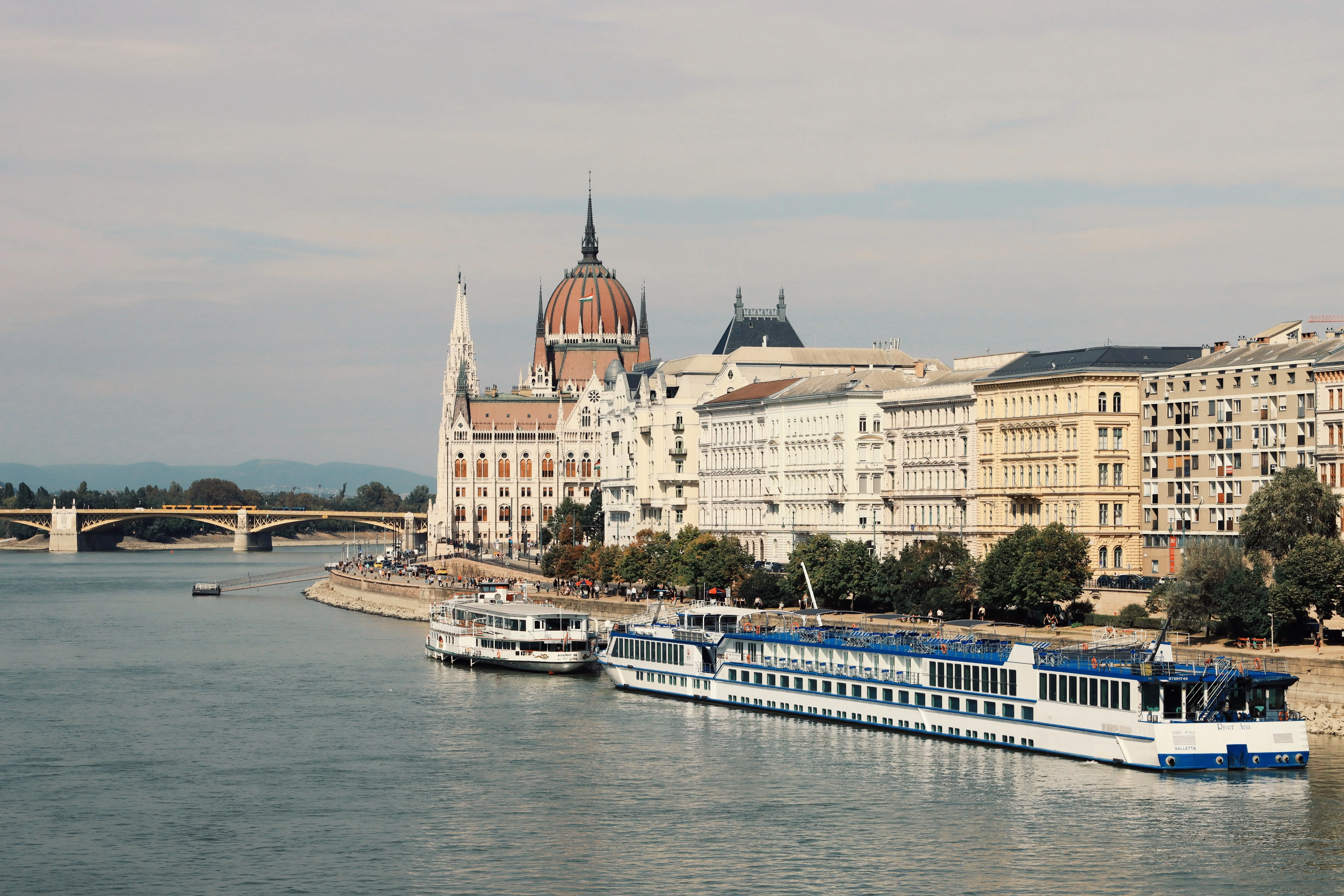 A river cruise ship moored beneath a domed parliament building
