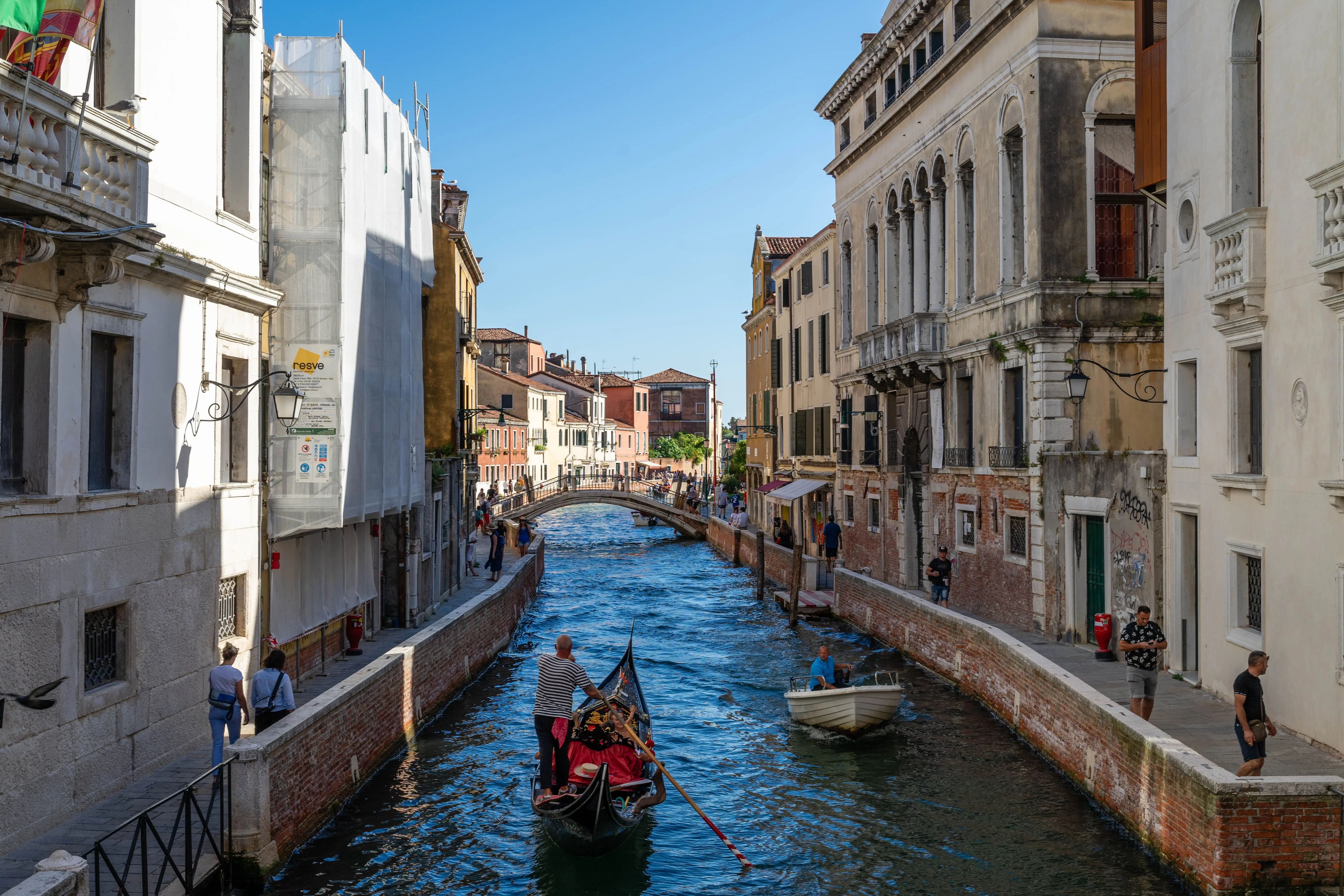 A gondola on a narrow Venetian canal between pastel buildings