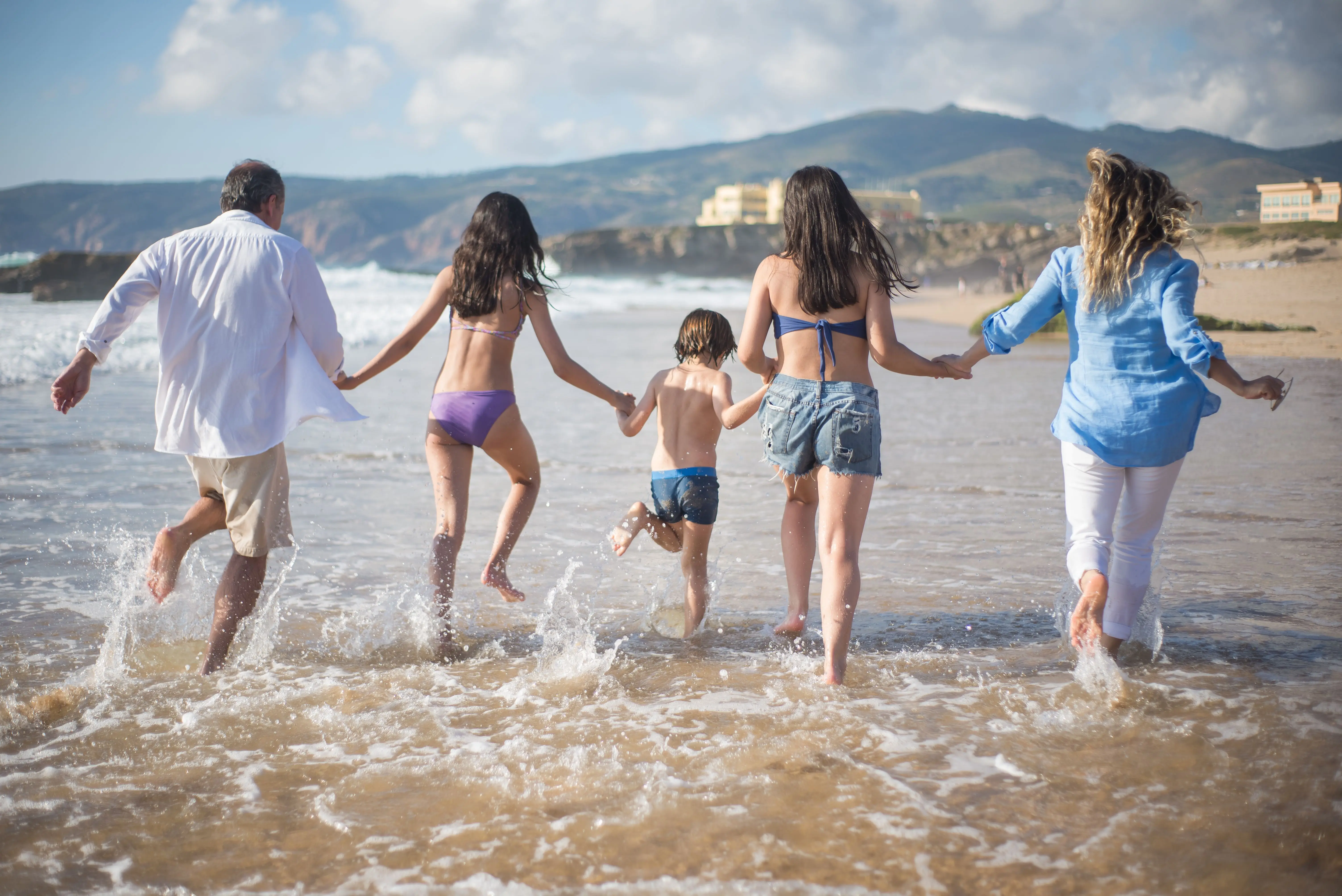 Parents and children running through the shallows on a sunny beach